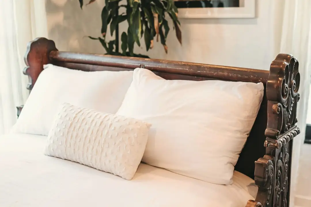 White pillows and linen against a carved timber headboard