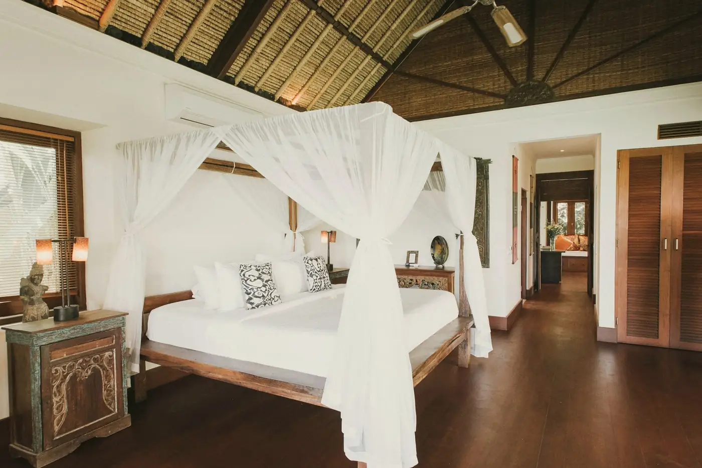 Canopy bed with white netting under a high pitched timber ceiling