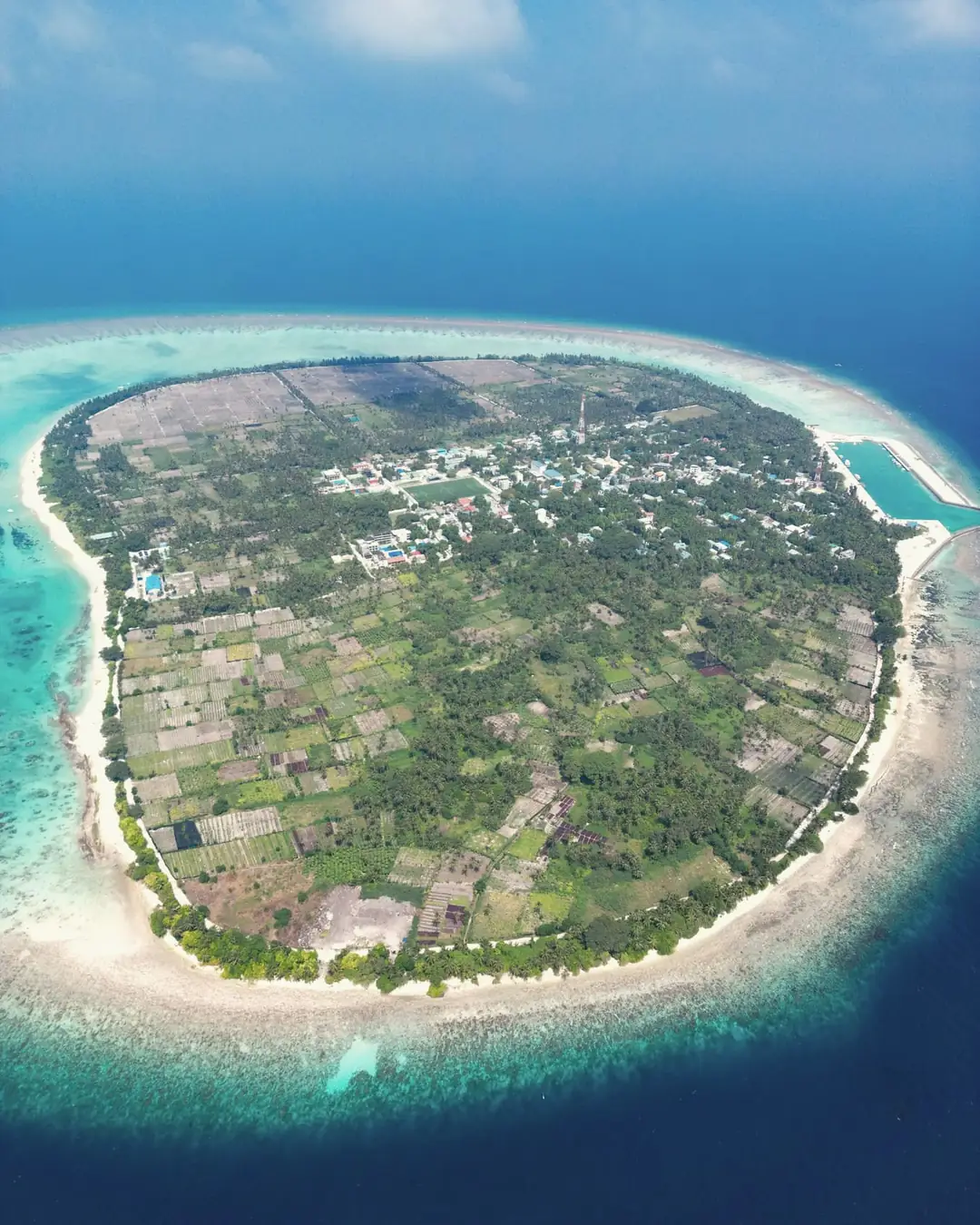 A local island from the air: rooftops, gardens and a turquoise lagoon