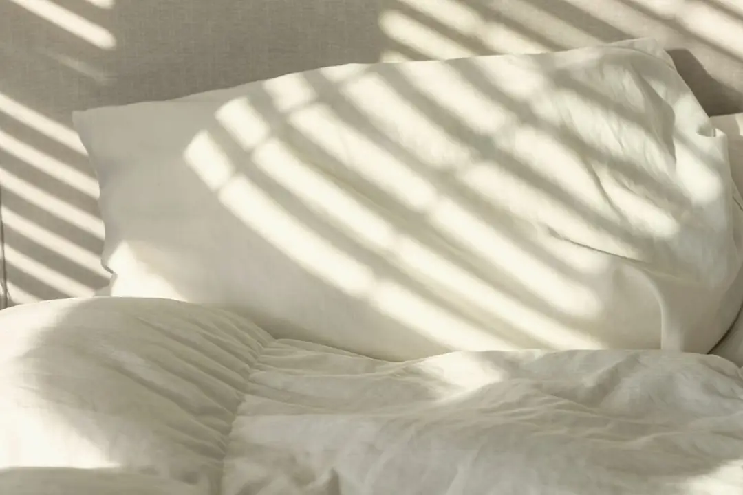 White linen pillows in morning light through the shutters