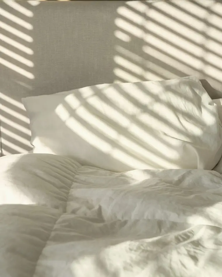 White linen pillows in morning light through the shutters