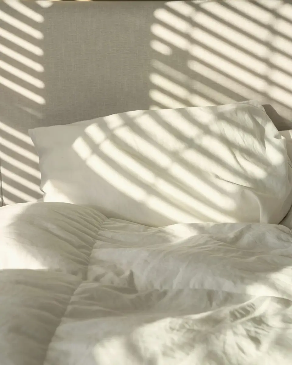 White linen pillows in morning light through the shutters