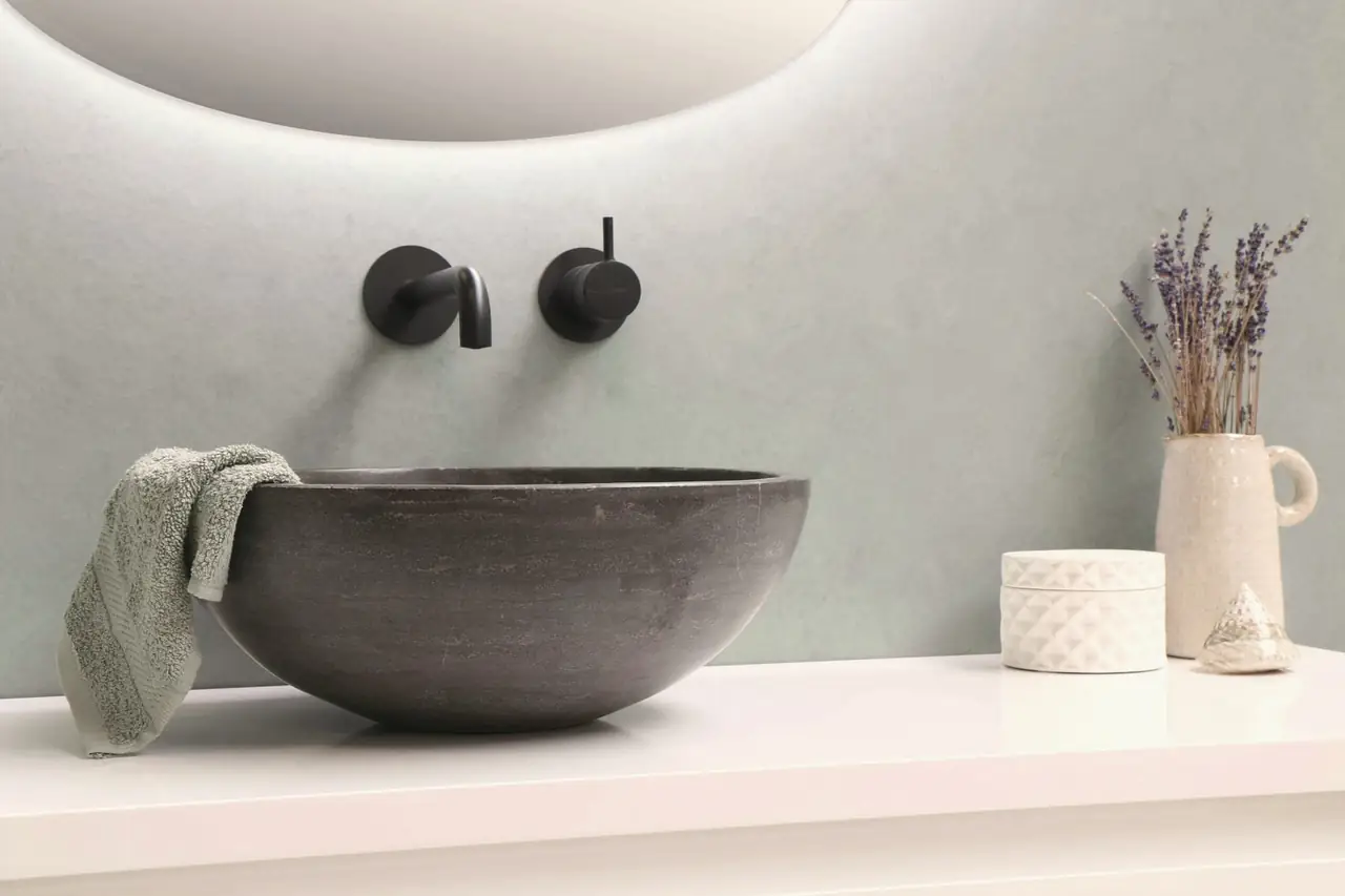 Stone basin on a white plaster shelf with dark brass taps