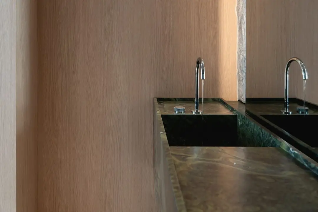 Stone counter with two basins in a timber-lined bathroom
