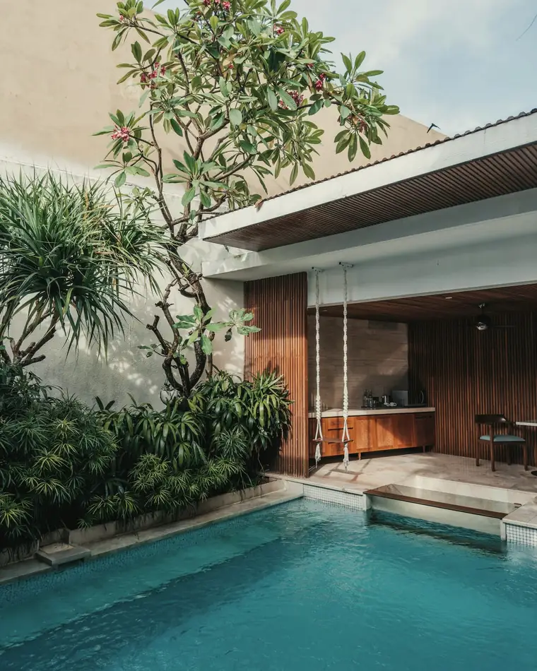 Teak-clad pavilion beside a walled courtyard planted with frangipani